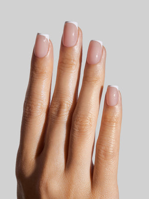 Hand with French Tip press-on nails on a plain background