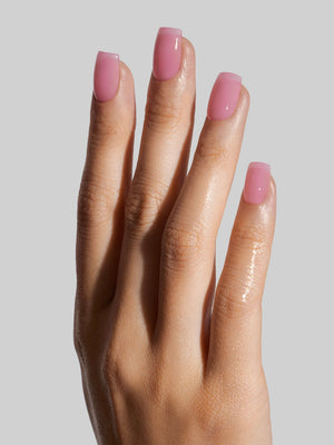 Hand with pink press-on nails on a plain background