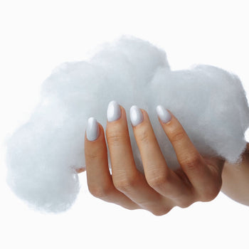 Female hand with silver nails holding puffy white cotton candy.